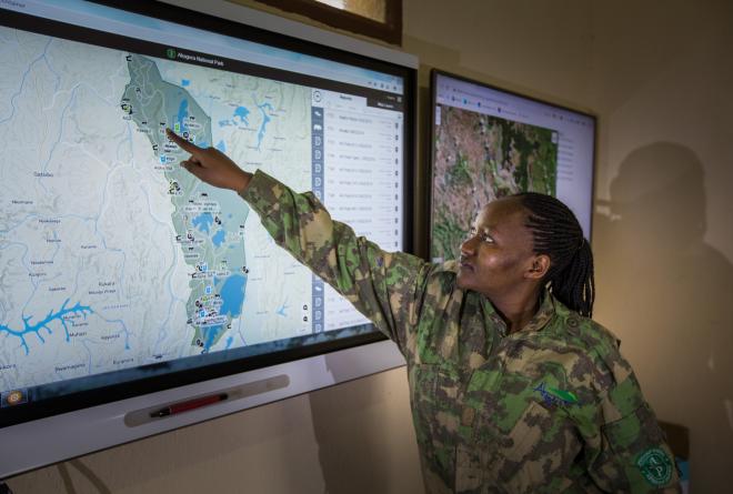 Ranger points at the Northwest portion of an Akagera National Park map on a flat screen TV at the front of a room © Scott Ramsay
